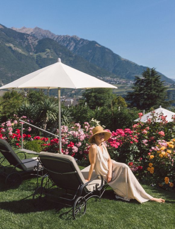 Frau richt an Blume im Garten des Giardino Marling